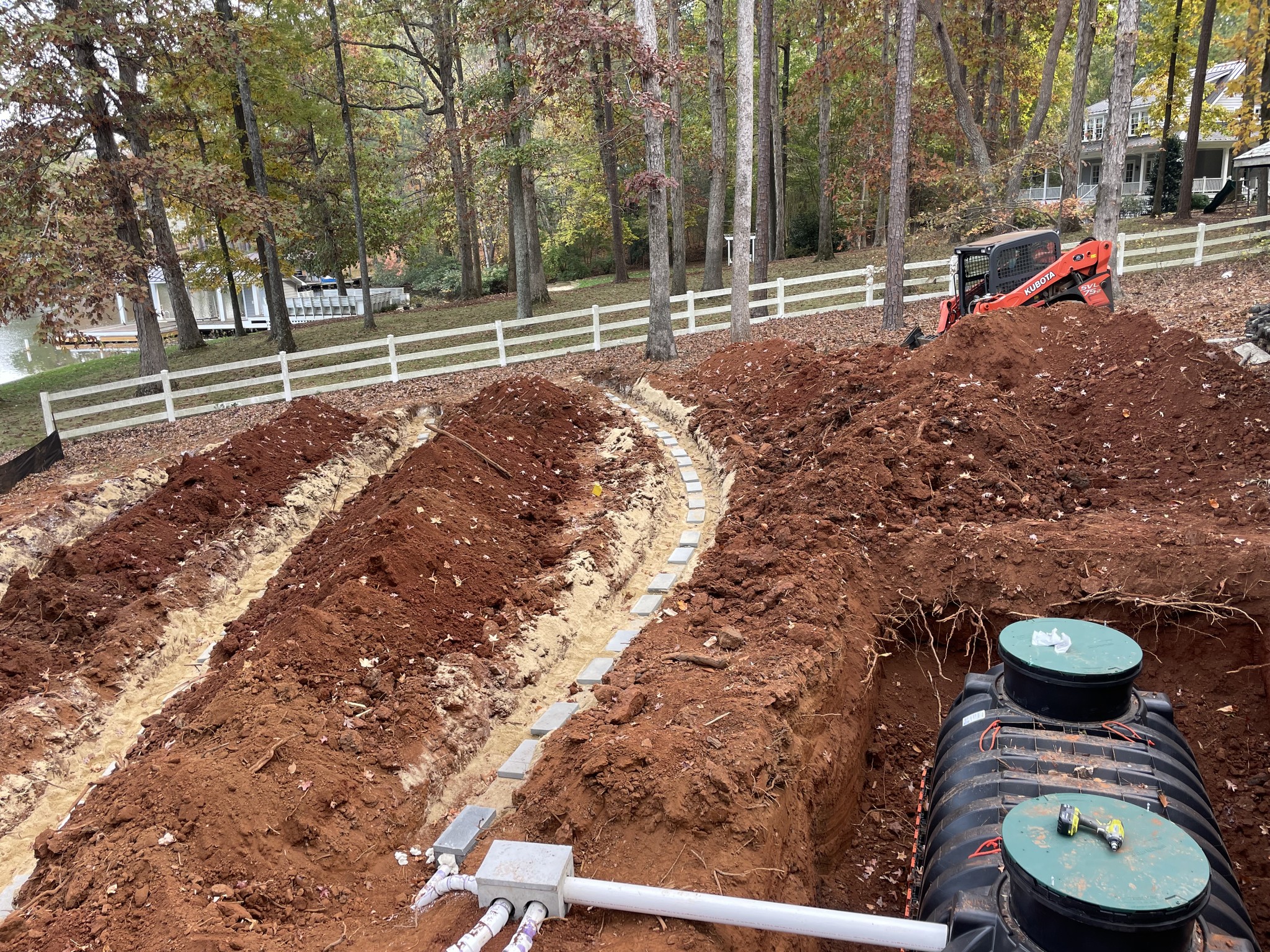 Excavated ground showing a septic tank and drainage system in a residential area.