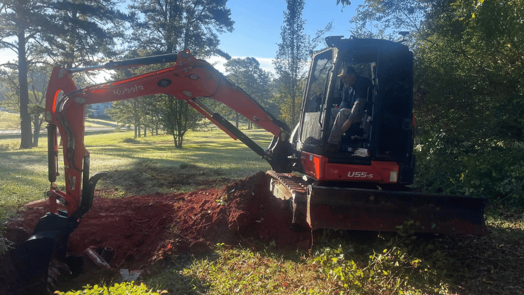 Kubota U55-4 excavator digging in a landscaped area with a person operating it.