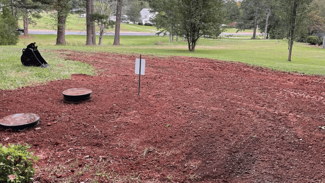 Excavated trench with red soil for septic system installation.