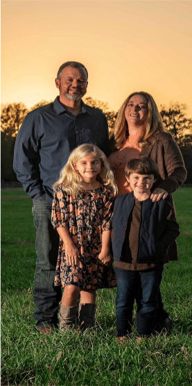 A family portrait featuring two children and two adults standing together outdoors during sunset.
