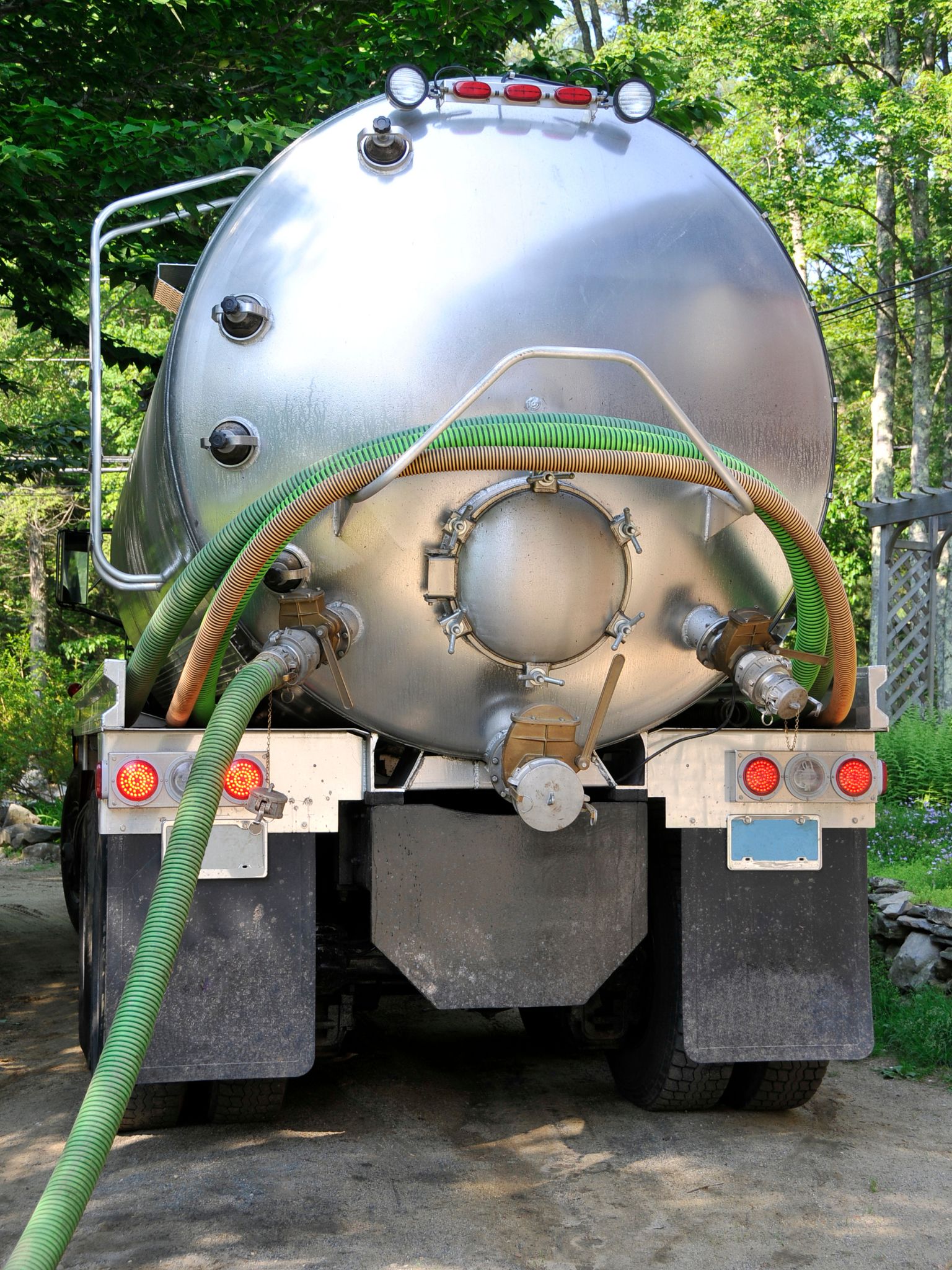 Rear view of a septic pumping truck with hoses attached for waste removal.